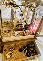 Front view of wooden box open showing hanging necklaces, ring rolls and top compartments