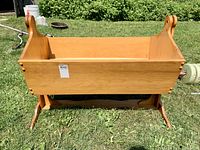 Side view of solid wood doll cradle showing natural finish and rocking base.