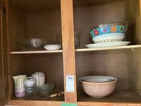 Pyrex nesting bowls full set, glass casserole dish, ceramic bowls, and pitchers on wooden shelves