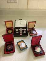 Photo showing a 1971 Canadian circulation coin set with 7 coins displayed in a black case alongside six individual commemorative coins in display boxes.