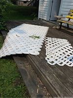 Overview of multiple white lattice panels stacked on wooden deck.
