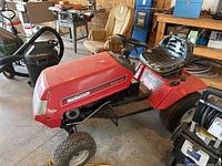 Full side view of the red Mastercraft ride-on lawnmower showing overall condition, steering wheel, seat, and front tire.