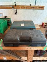Two closed plastic cases on shelf, one black, one blue, showing general lot items.