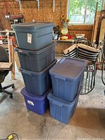 Full view of six plastic storage totes stacked in a garage.