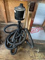 Full view of Little Giant sump pump with black motor housing and coiled black flexible hose.