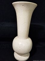 Full view of the large stone vase showing its full height, shape, and color against a black background.