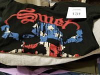 Black t-shirt with red and blue graphic print showing brand 'Smax' or similar, folded on surface