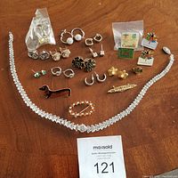 Photo showing entire lot including crystal necklace, earrings in various styles and pins with floral and national themes