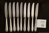 Nine Gorham silver plate dinner knives arranged in a single row showing full length with a MaxSold lot card; blades and handles visible