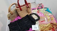 Four handbags displayed on a table including a beige and brown handbag with wooden handles, straw handbag with red handles, black fringed handbag with clear handle, and a colorful fabric tote bag with floral and crane design.