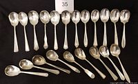 Full lot of 21 silver plate sugar spoons laid out in two rows showing different handle styles and bowl shapes.