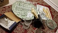 Overview of kitchen items including wire plate holders, cutlery block with knives, glassware, ceramic plate, and jar.