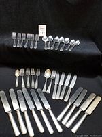 Full lot on black background, showing knives, forks and spoons arranged in rows