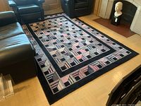 Full view of wool pile carpet on wood floor between black leather furniture.