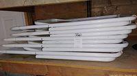 Stack of five white metal folding chair frames stacked horizontally.