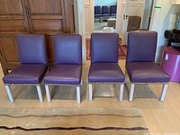 Front view of four purple leather dining chairs in a row