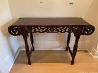 Front view of wood console table with carved scrollwork details showing overall condition.