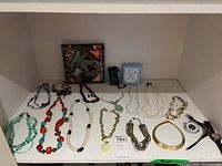 Front view of necklaces arranged on shelf with watch