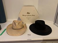 Two Stetson hats displayed with a single hat box labeled 'Margo's Custom Hats'. The hats include a tan straw hat and a black wool felt hat.