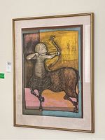 Framed lithograph showing a centaur archer with geometric background, the print appears loose within the gold frame.
