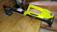 Ryobi P2109 leaf blower with attached battery placed on wooden surface
