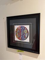 Framed print with abstract circular design, showing front view mounted on a wall.