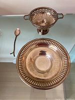 Overview photo of the sterling pierced bowl, shallow dish, and spoon displayed together on a glass surface.
