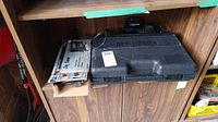 Black & Decker Jig Saw box and Hitachi drill case and charger on wooden shelf