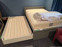 Photo showing side view of the trundle bed pulled out with single mattress and double mattress on top with bedding.