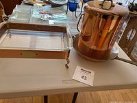 Photo of rectangular copper chafing dish with glass insert on plastic table.