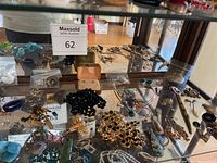 Full display cabinet with various costume jewelry pieces including necklaces, bracelets, brooches, earrings, and rings in assorted colors and styles.