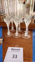 Set of six Fabergé champagne flutes arranged closely together on a wooden surface, showing the full set.