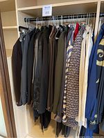 Photo of clothing rack showing dark suits, blazers, and patterned jackets for women.