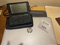 Front view of HP laptop with Sharp Zaurus PDA on top, showing keyboard and screen of PDA