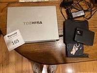 Silver Toshiba laptop closed, showing Toshiba logo and auction tag.