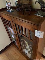 Side-angle view of dark brown oak cabinet showing slatted top rail, glass-front door and cabinet side