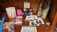 Shelf with various items including the I Love Lucy print, RBG figurine, Feminist Flair cards, decorative wooden knife plaque, and other items.