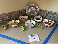 Full view of the set on kitchen counter including silver-plated serving tray, five ceramic vegetable dishes, and three green ceramic peas in pod salt and pepper shakers.