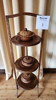 Full view of the three-tiered wooden stand with the three carved wooden containers placed on each tier.