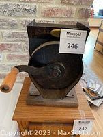 Front view of vintage manual coffee/grain grinder showing hand crank with wooden handle mounted on wooden base.