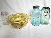 Photo showing all jars and two nested amber depression glass mixing bowls grouped together on white background.
