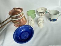 Photo showing the full lot: blue Ralston cereal bowl, copper double boiler with brass handles and inner pot, white USPS ZIP+4 coffee mug, Pillsbury salt and pepper shakers, Bailey's teacup, and vintage sugar dish