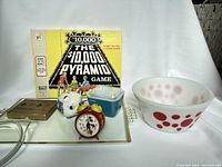 Full lot composition showing The $10,000 Pyramid board game, Mickey Mouse alarm clock, blue Pyrex container, Federal Glass polka dot bowl, and a tray