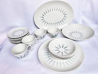 Full set of Royal China Aurora dishes displayed showing various plates, cups and bowls with blue atomic diamond pattern.