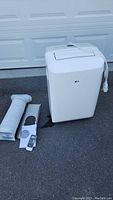 Full view of air conditioner unit with exhaust hose, window kit, remote and manual laid out