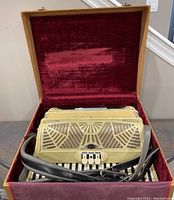 Ivory-colored Lorio Candido accordion inside red velvet lined case with straps visible