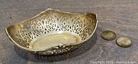 Top angled view of the sterling silver pierced dish with two silver dimes on a wooden surface.