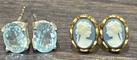 Photo shows two pairs of earrings together: one blue stone set in sterling silver, other blue cameo with gold-tone setting.