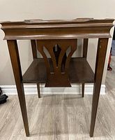 Front view of vintage wooden side table showing decorative cut-out back panel and legs.