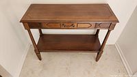 Front view of walnut entrance table showing drawer, legs, and lower shelf.
